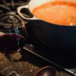 Tomato Sauce - It's All In The Blend cooking on stove with wine glass and wooden spoon