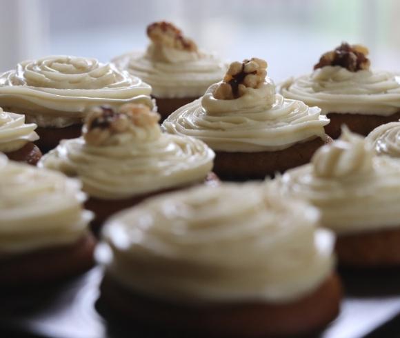 The Ultimate Pumpkin Bread Recipe image showing how versatile the pumpkin bread recipe is by making the batter into muffins with swirled cream cheese frosting on top along with a single walnut in the center of them instead of making pumpkin bread loaf