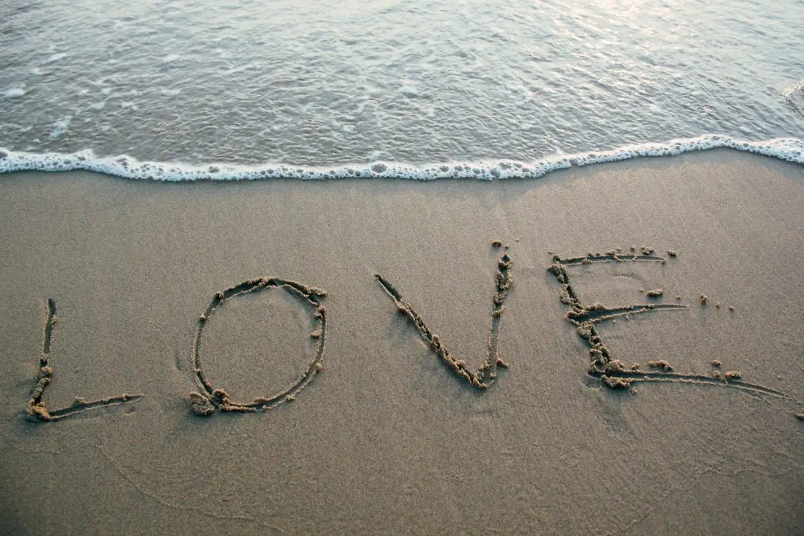 Stay Safe In The Sun! How To Make Organic Sunscreen love written in sand on waters edge at the beach