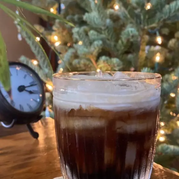 Kahlua - A Simple Homemade Recipe image showing a cocktail glass of kahlua and cream with background christmas tree