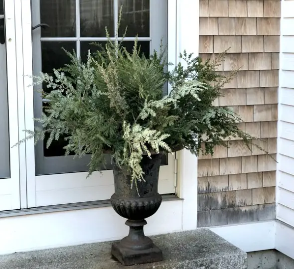 How To Decorate Outdoor Hangers For Winter image of greenery in rod iron urn