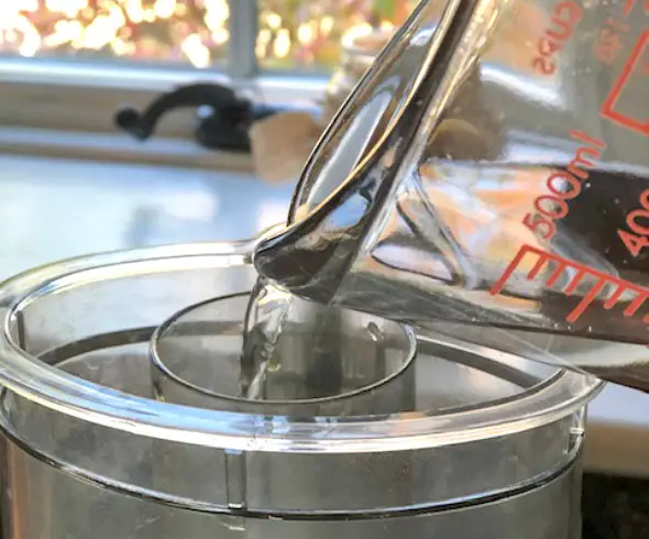 Easy Homemade Flatbread Crackers image of water being drizzled into food processor