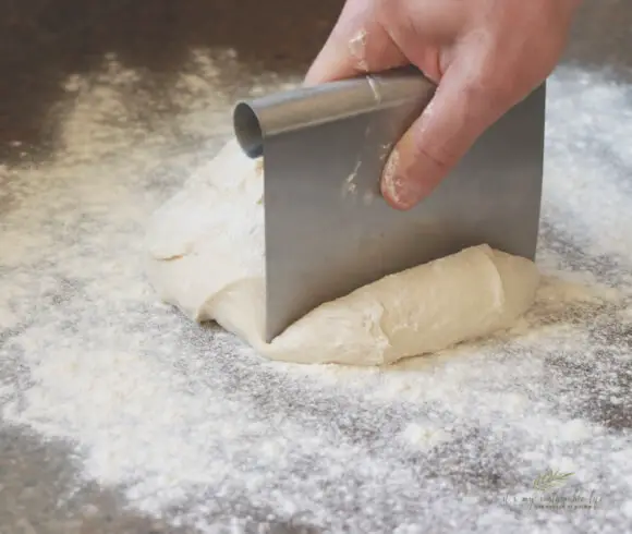 Homemade Hamburger Buns dividing dough into portion sizes using a kitchen scrapper