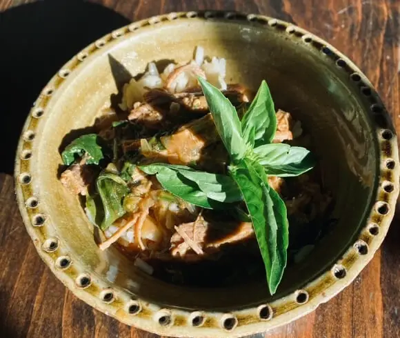 One Pot Thai Beef Curry with jasmine rice in beautiful green bowl with sprig of bright green basil on top