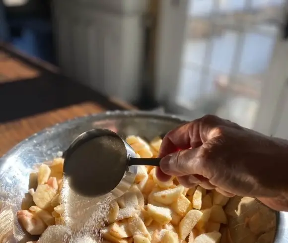 Homemade Gluten-Free Apple Crisp image of sliced apples with sugar being sprinkled over them