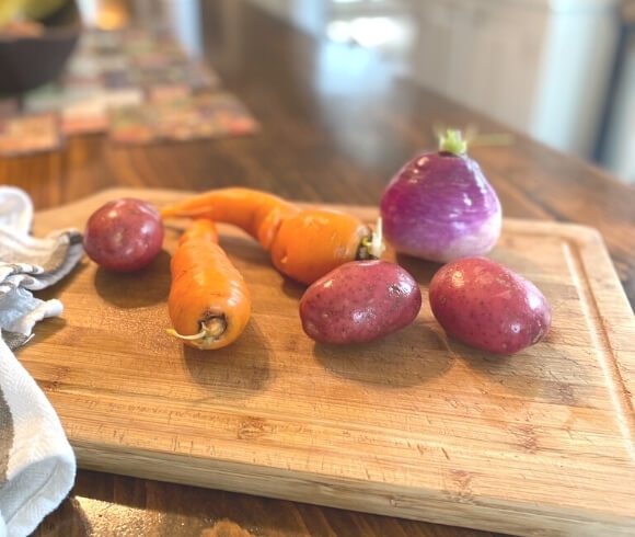 Easy Homemade Beef Stew image showing potatoes, carrots, and turnip on cutting board