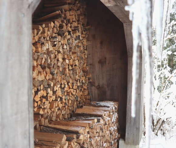 Heating With wood image of wood stacked in two rows in woodshed