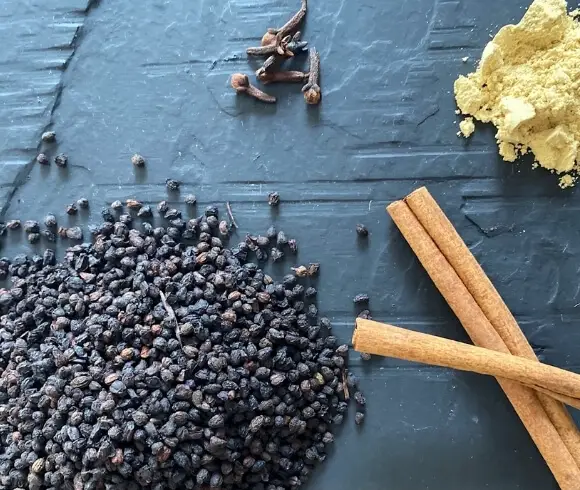 Home Apothecary Essentials image showing dried berries, herbs, and spices layed out on slate board