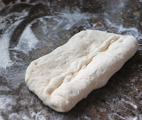 Homemade Baguettes image showing rectangle of dough on floured stone surface