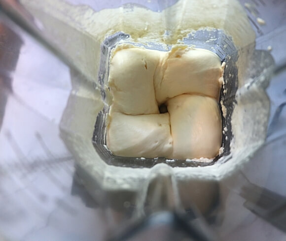 How To Make Homemade Butter {And Buttermilk} image showing view looking down into blender with progression of turning cream into butter