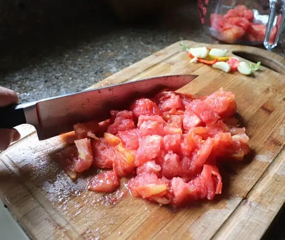 New England Style American Chop Suey image showing large knife slicing fresh tomatoes on a cutting board