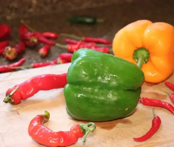 Homemade Hot Pepper Jelly image showing fresh red and yellow peppers resting on cutting board