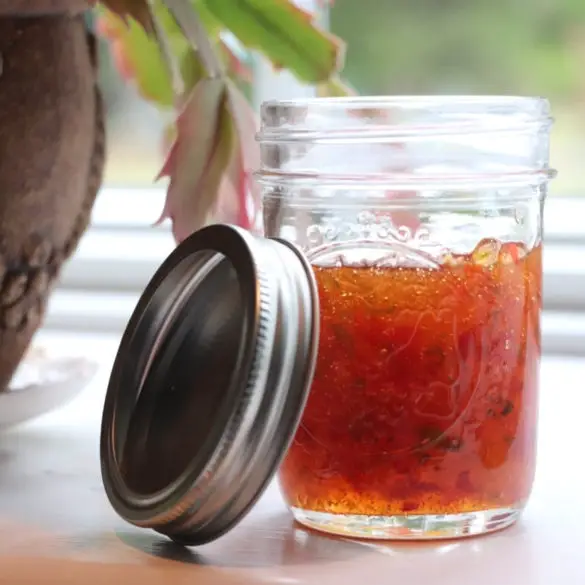 Homemade Hot Pepper Jelly featured image showing partially filled mason jar with lid resting on the side of the jar