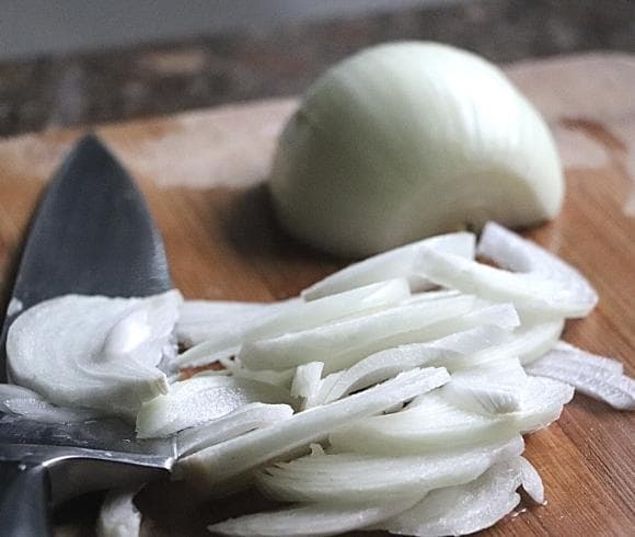 Old Fashioned Corn Chowder Recipe image showing sliced fresh onion with half peeled whole onion on cutting board with knife