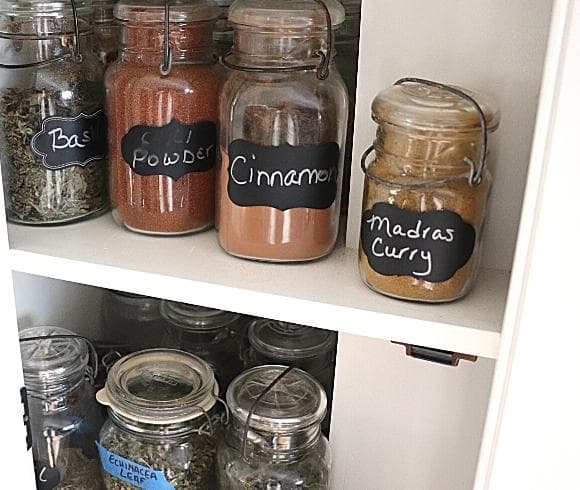 Pantry Inventory {Creating A Simple System That Saves Money} image showing antique mason jars with bale wire tops filled with spices in apothecary cupboard