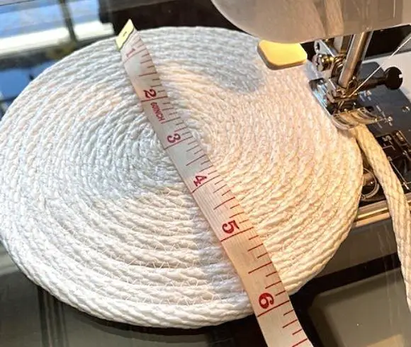 Rope Bowl Tutorial image showing white rope mat resting by sewing machine with a red and white tape measure laying on top displaying 6 inches