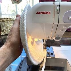 Rope Bowl Tutorial image showing hand holding the rope bowl completely vertically, right against the Janome sewing machine while stitching