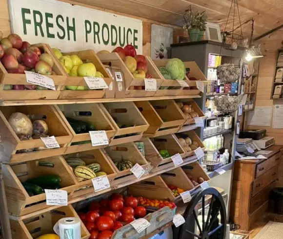 HOW TO EAT SEASONALLY {A GUIDE TO SEASONAL EATING} image showing fresh produce displayed in wooden boxes by a local farm stand, Little Red Hen Farm