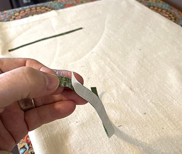 How To Appliqué image showing hand holding motif and peeling the paper backing off the fabric