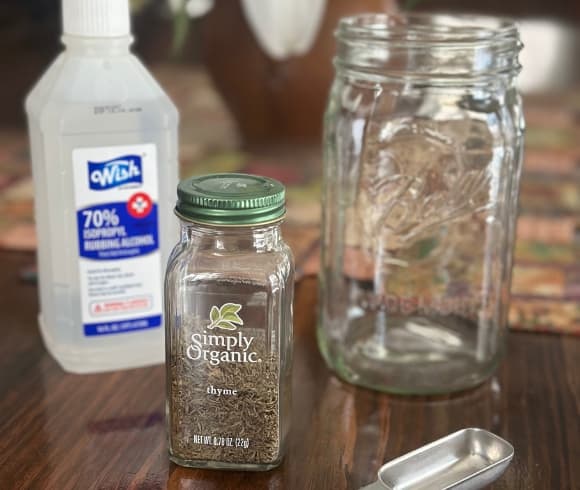 How To Sanitize Seed Trays image showing supplies needed (bottle of rubbing alcohol, organic dried thyme, measuring spoon, and jar) to make a thymol tincture